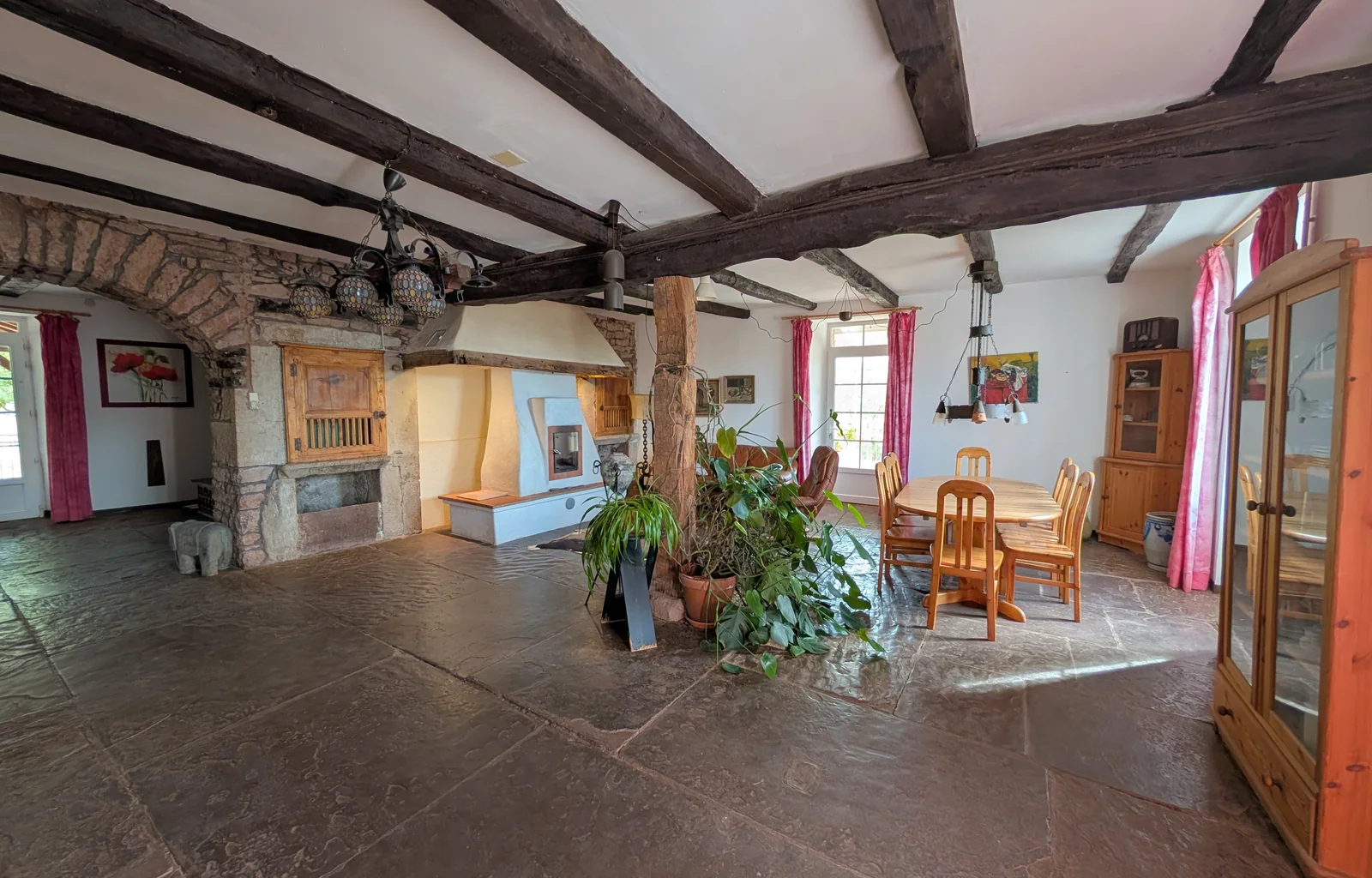 Une grande pièce de vie de la maison historique, avec ses poutres et ses espaces pour se retrouver.